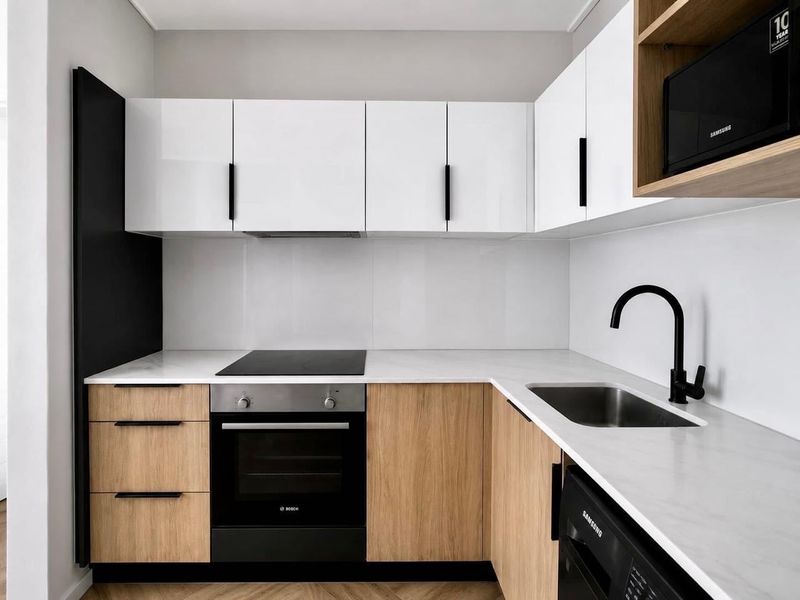 Modern kitchen featuring white and wood-tone cabinetry, stone countertops, integrated oven, electric hob, and a sleek black mixer tap.