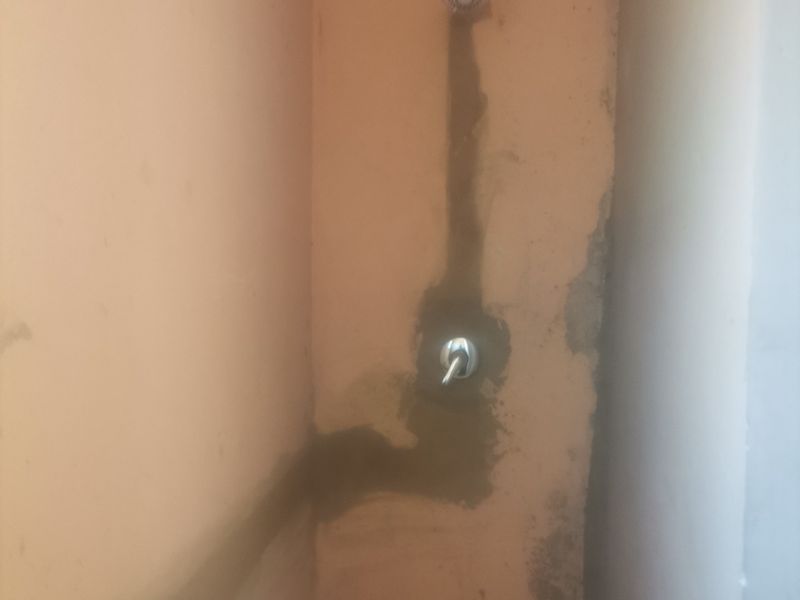 A bathroom space featuring a shower and pedestal basin, currently requiring wall finishing and cosmetic repairs to the plasterwork.