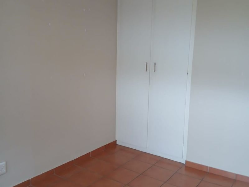 An empty bedroom featuring tiled flooring, a built-in cupboard, and a ceiling fan.
