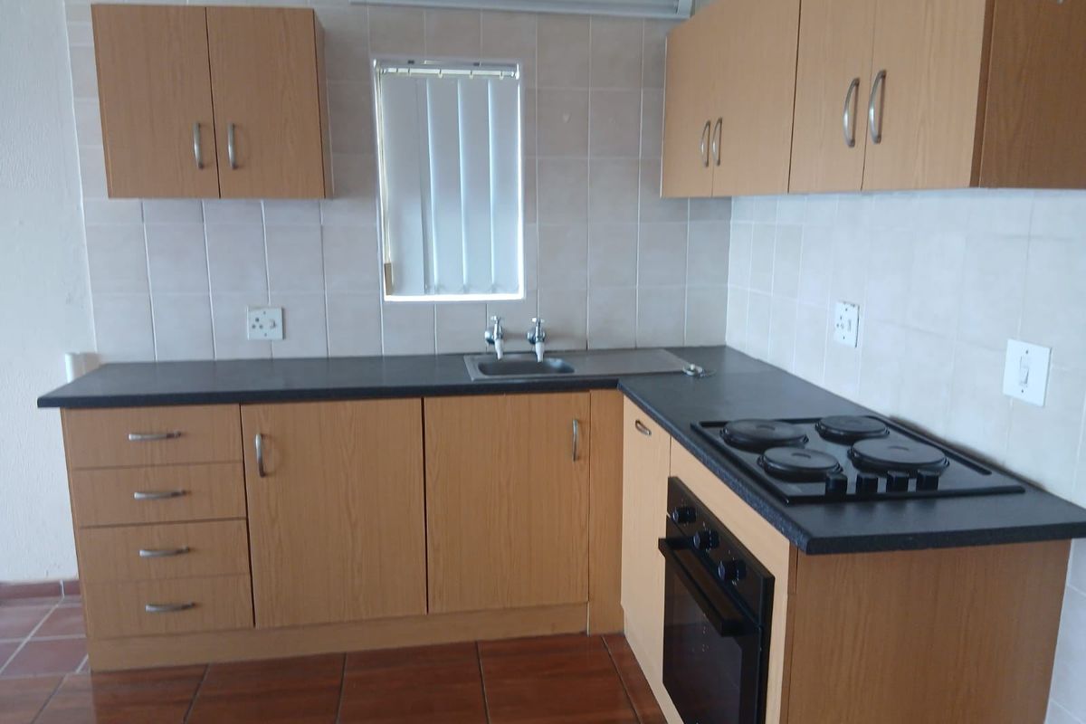 A functional kitchen featuring laminate cabinetry, built-in oven, electric hob, tiled backsplash, and durable tiled flooring.