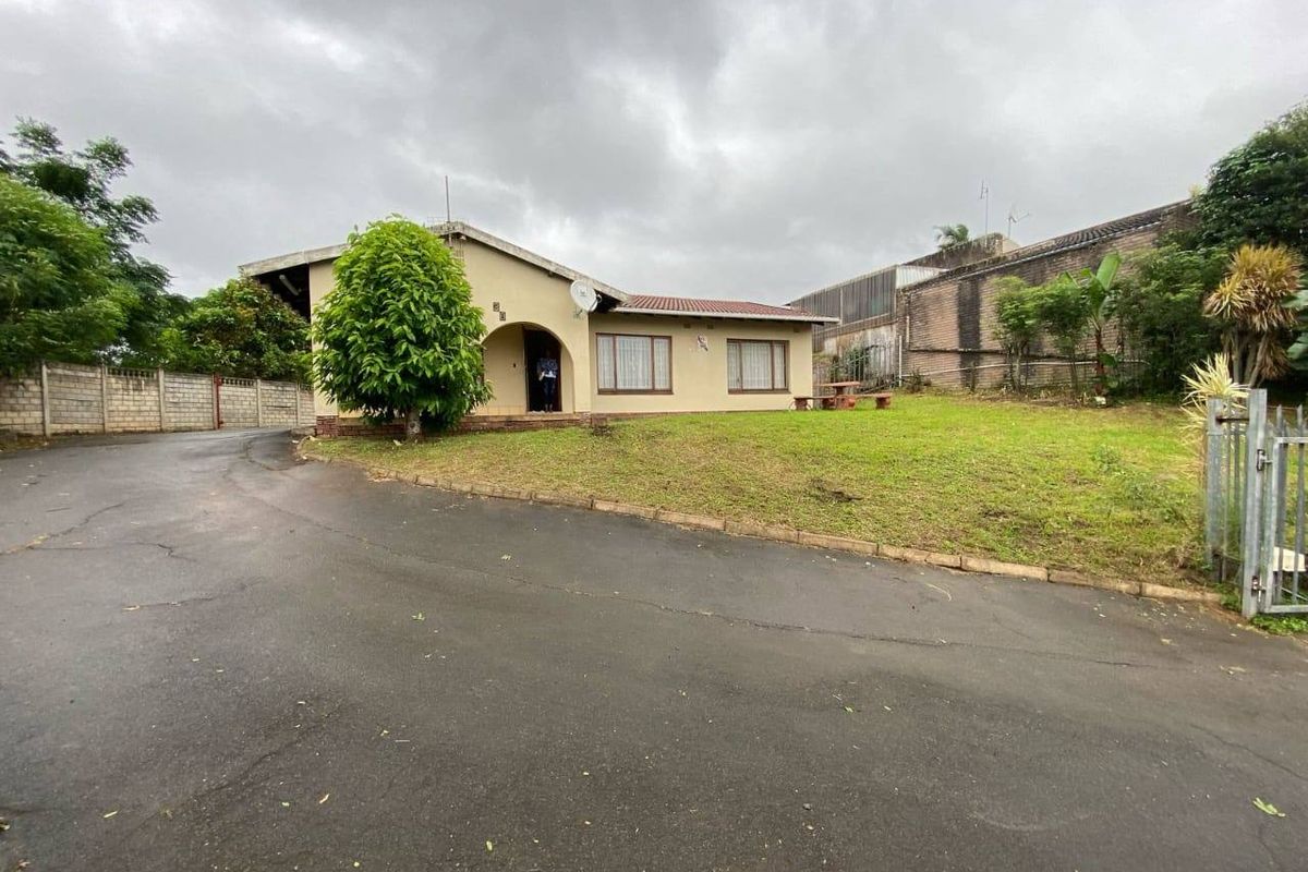 Front view of a single-story house featuring a tiled roof, concrete driveway, and perimeter walling on a spacious corner lot.