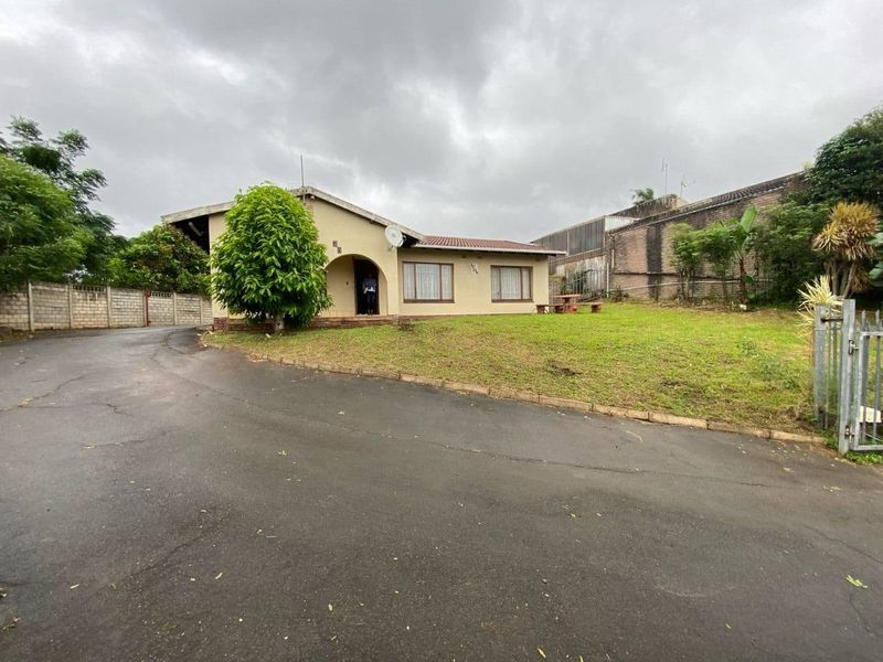 Front view of a single-story house featuring a tiled roof, concrete driveway, and perimeter walling on a spacious corner lot.