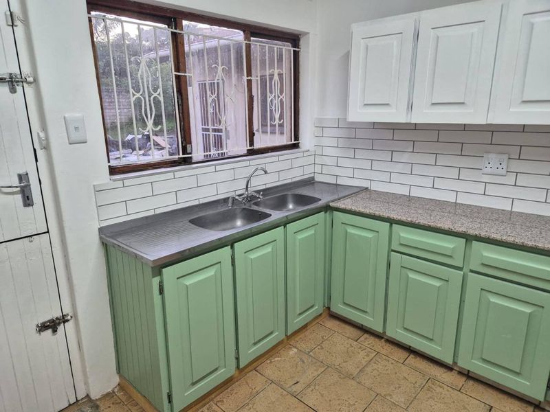 A functional kitchen featuring a double stainless steel sink, granite countertops, subway tile backsplash, and ample storage cabinetry.