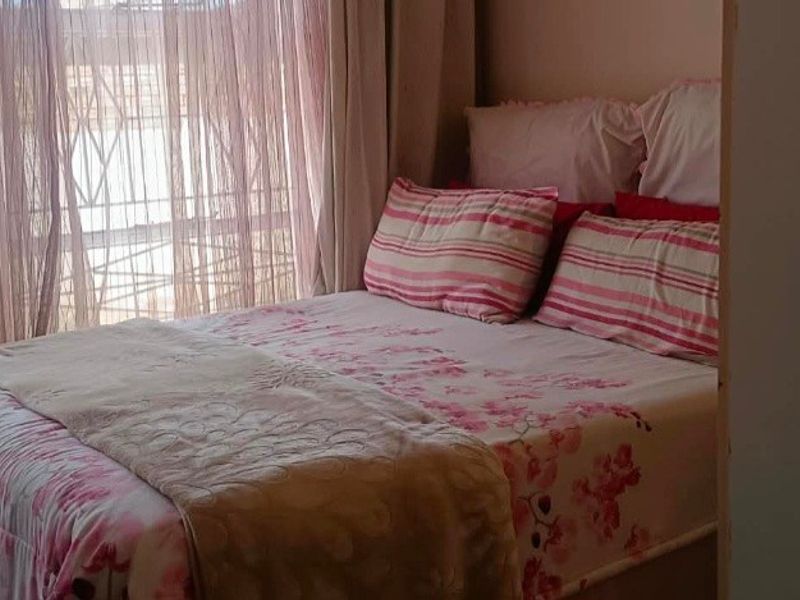 A bedroom featuring a window with installed curtain tracks, providing natural light to the space.