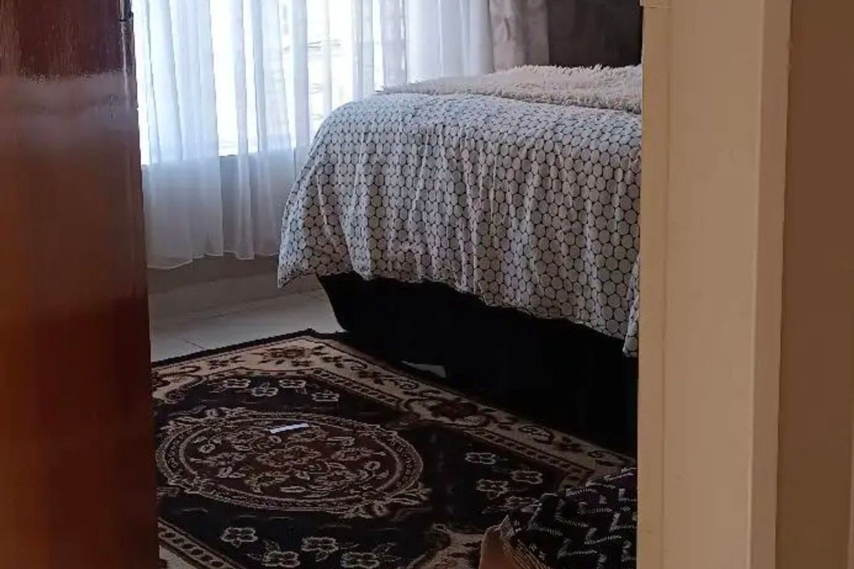 A bedroom featuring tiled flooring and natural light through window curtains, viewed from the doorway.