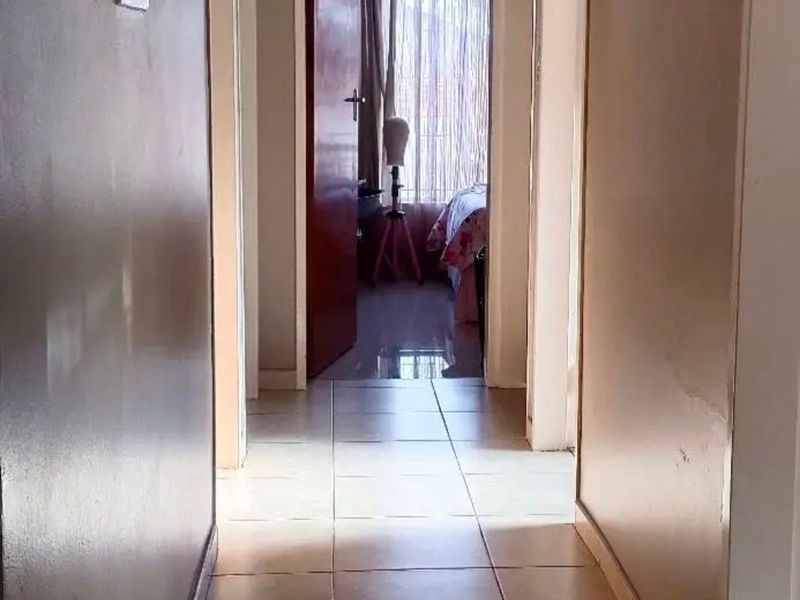 A functional hallway featuring neutral tiled flooring and access to multiple rooms, providing a central circulation space within the home.