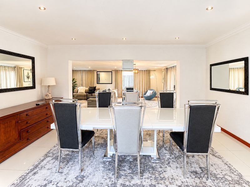 Spacious open-plan dining and living area featuring neutral tiled flooring, recessed downlighting, and coved cornicing, creating a bright and cohesive living space.