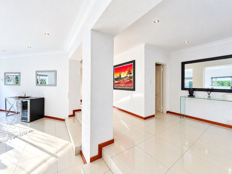 A bright and spacious hallway featuring polished tiled flooring, recessed downlighting, and coved cornicing, connecting multiple areas of the home.