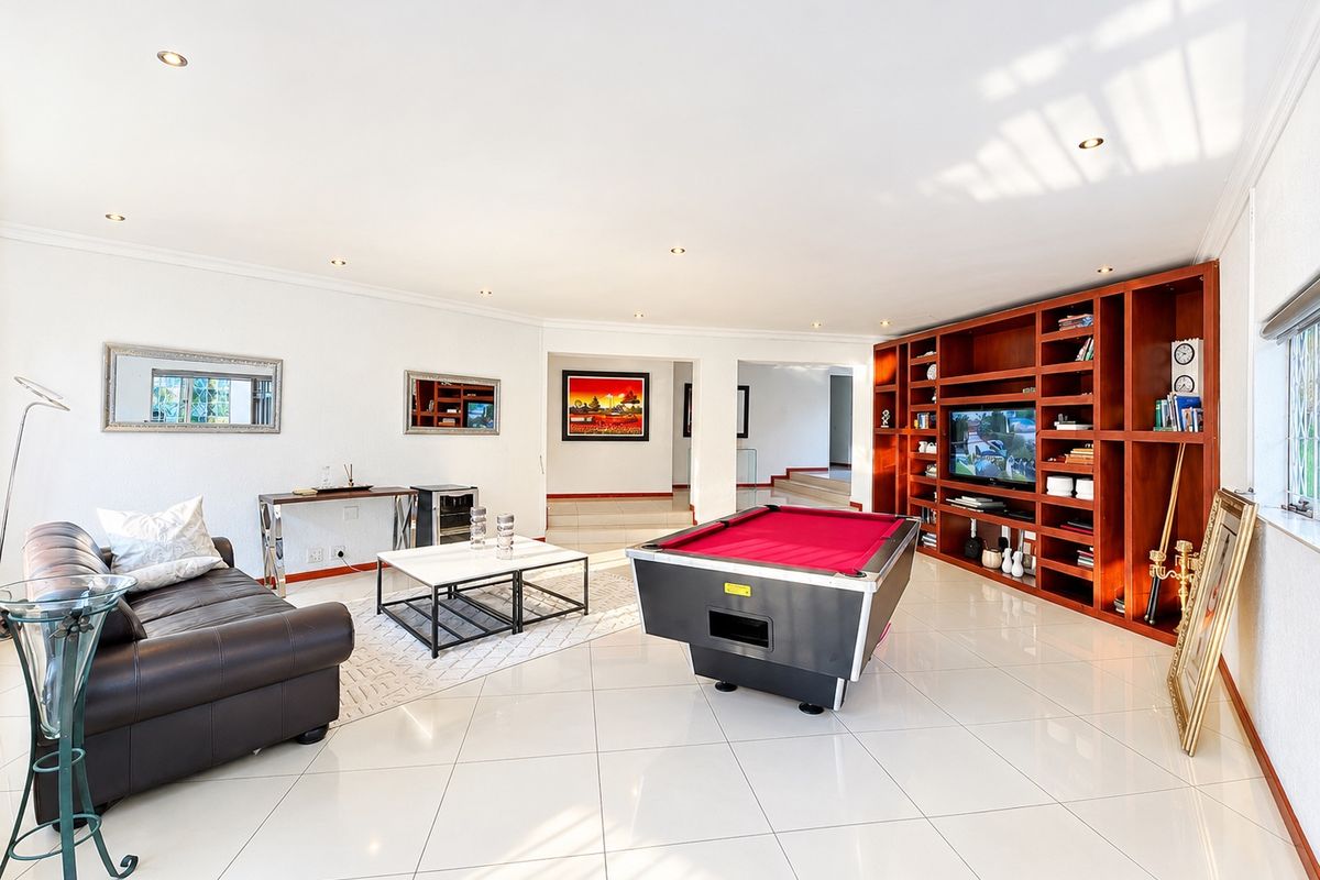 Spacious living area featuring polished porcelain floor tiles, recessed downlighting, and a large custom-built wooden wall unit for storage and media.
