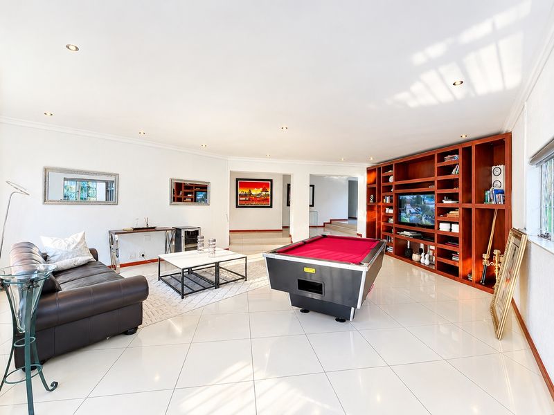 Spacious living area featuring polished porcelain floor tiles, recessed downlighting, and a large custom-built wooden wall unit for storage and media.