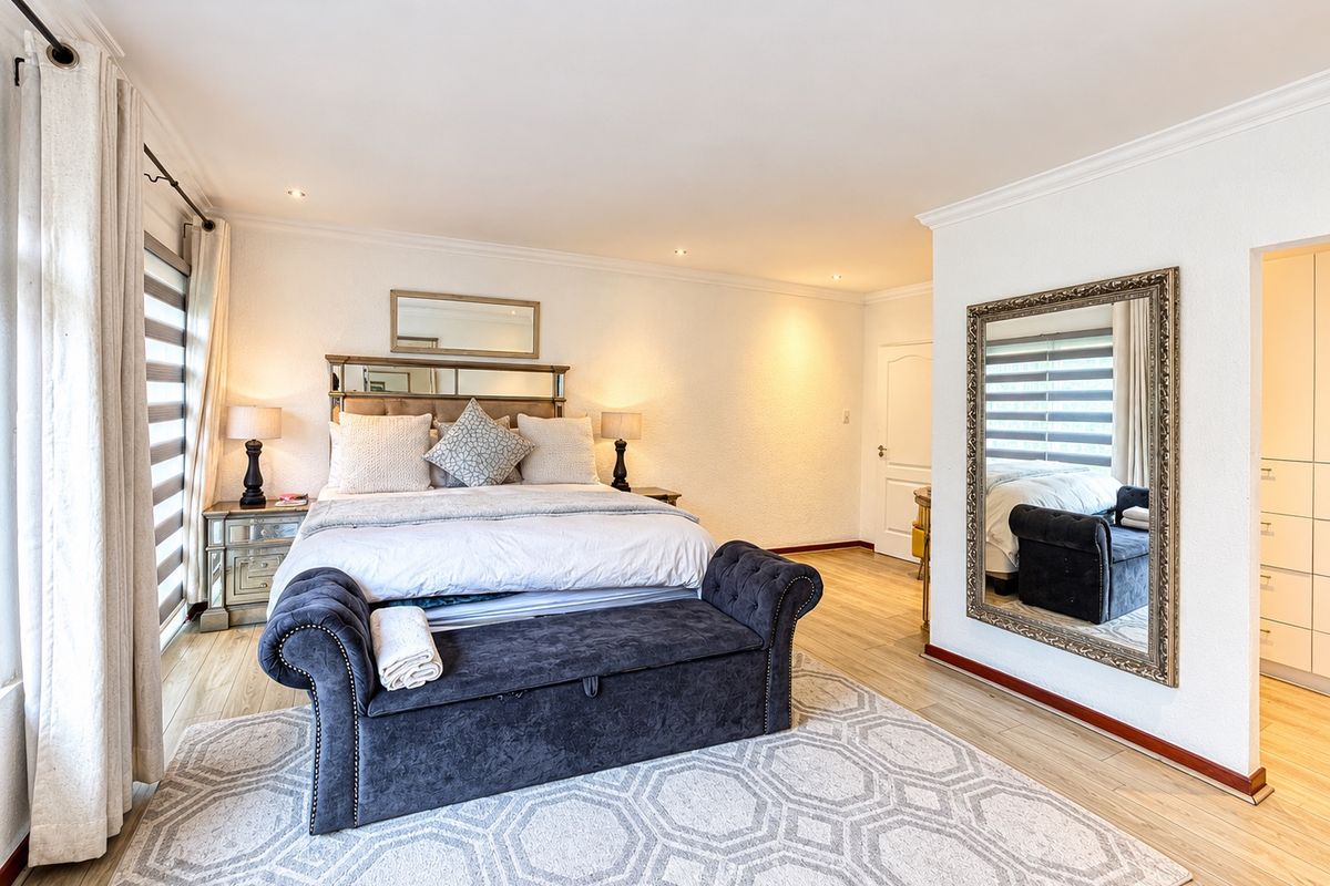 A well-maintained bedroom featuring laminate flooring, recessed downlighting, and built-in cupboard storage.