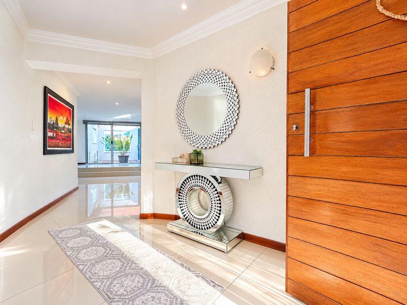 Welcoming entrance foyer featuring a solid timber front door, polished porcelain floor tiles, and elegant recessed lighting.