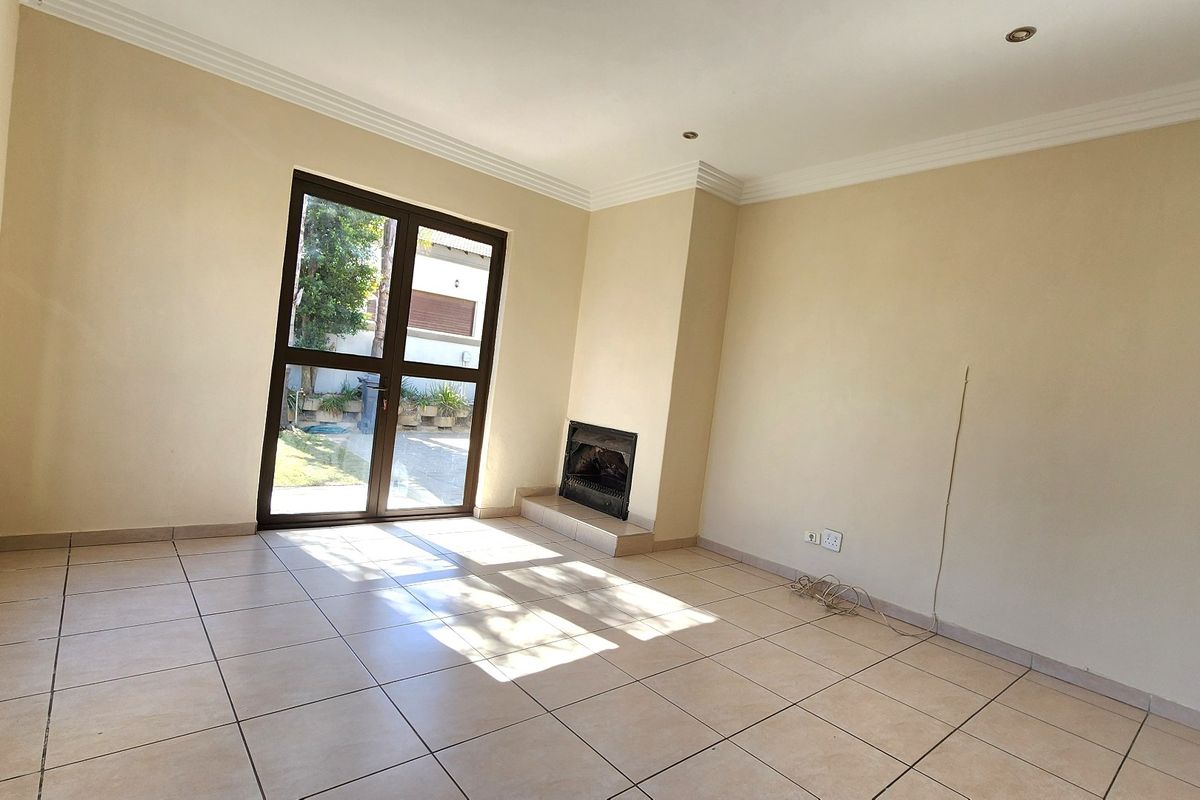 Spacious living room featuring tiled flooring, a built-in fireplace, and glass doors providing direct access to the outdoor area.