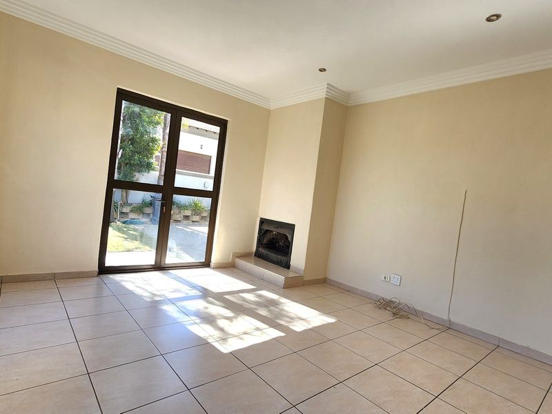 Spacious living room featuring tiled flooring, a built-in fireplace, and glass doors providing direct access to the outdoor area.