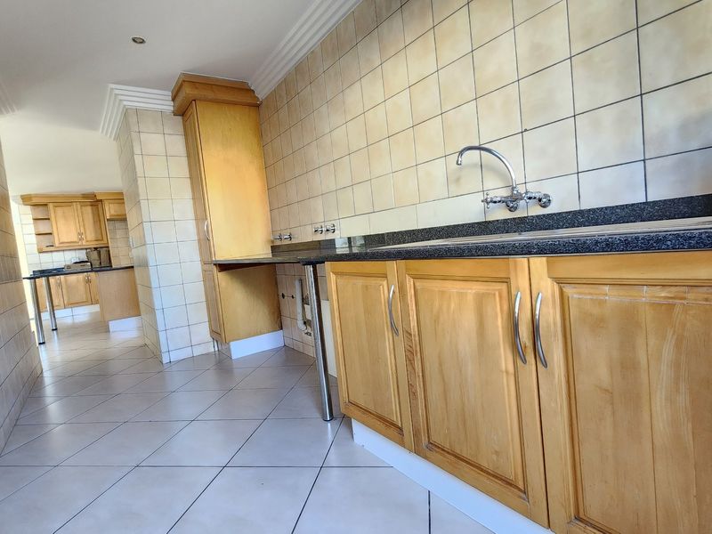 A functional kitchen area featuring light wood cabinetry, granite countertops, tiled splashbacks, and tiled flooring, offering a clean and practical workspace.