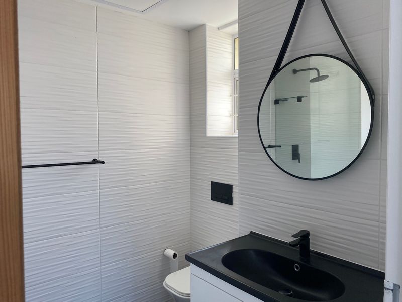 Modern bathroom featuring textured white wall tiles, a sleek black vanity basin with matching fixtures, and a wall-mounted toilet.
