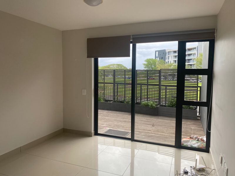 An empty living area featuring large sliding glass doors that open onto a private wooden deck with a privacy screen.