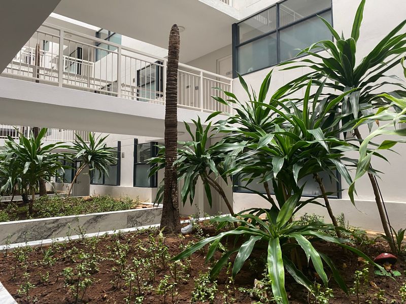 A well-maintained apartment complex courtyard featuring a landscaped garden bed with marble edging and elevated walkways with metal balustrades.