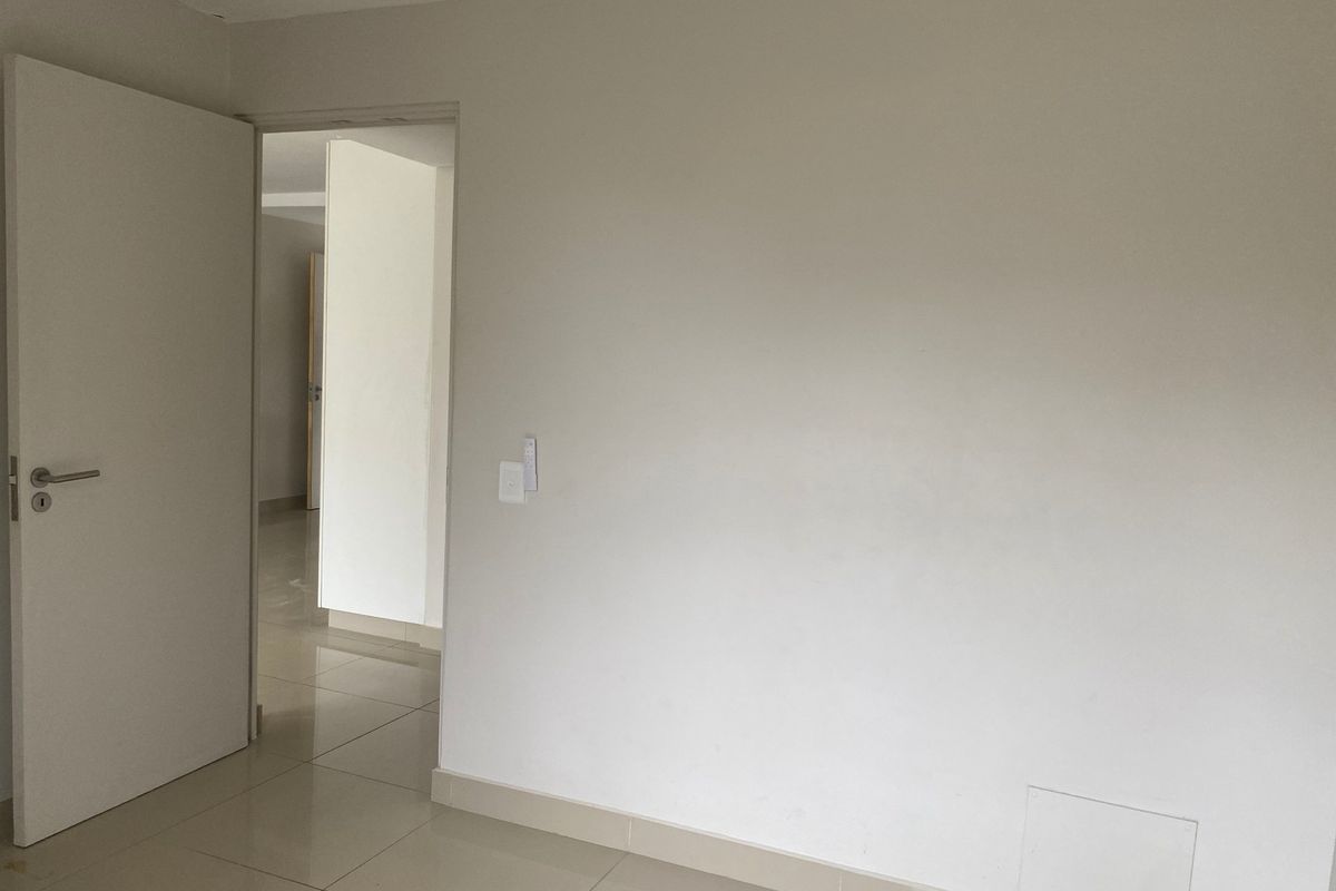 A clean, empty bedroom featuring neutral walls, tiled flooring, and a standard internal door, offering a blank canvas for personalization.