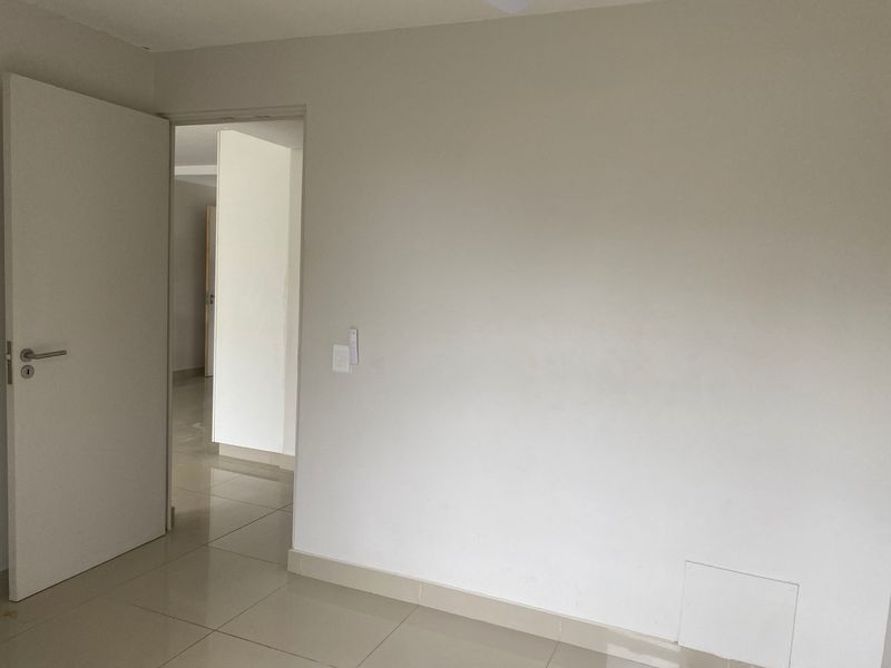 A clean, empty bedroom featuring neutral walls, tiled flooring, and a standard internal door, offering a blank canvas for personalization.
