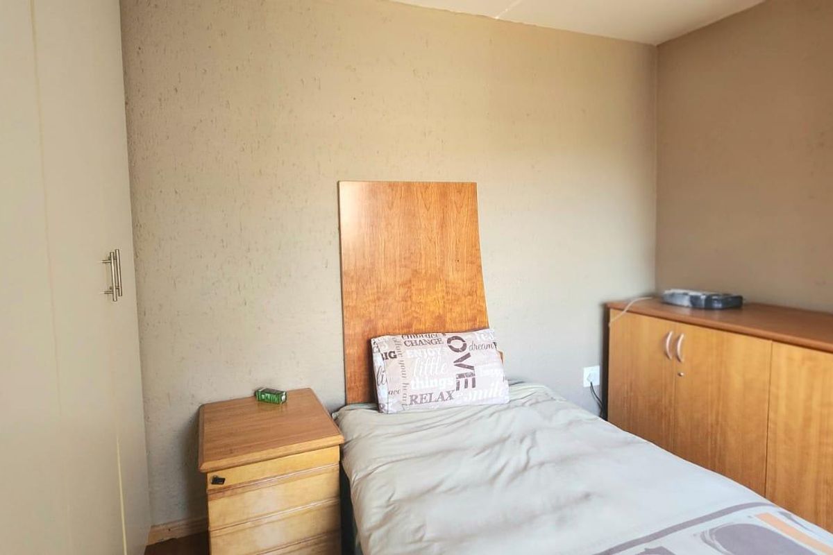A compact bedroom featuring built-in wardrobes and additional built-in storage cabinetry, providing functional space within the room.