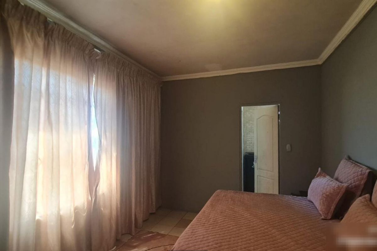 A bedroom featuring tiled flooring and crown molding, with a doorway leading to an adjacent space.