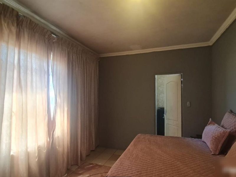A bedroom featuring tiled flooring and crown molding, with a doorway leading to an adjacent space.