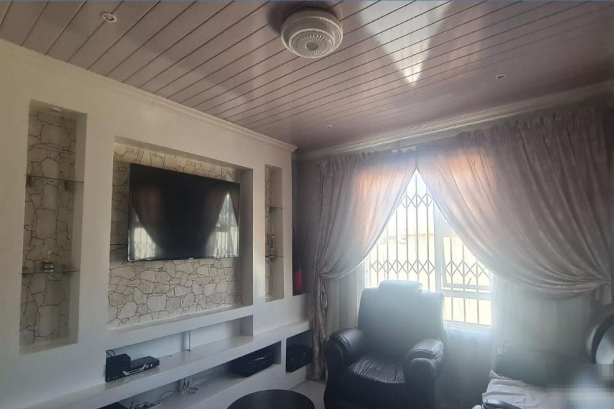 A cozy living room featuring a built-in media unit with stone-cladding accents and timber-look ceiling paneling, providing a functional entertainment space.