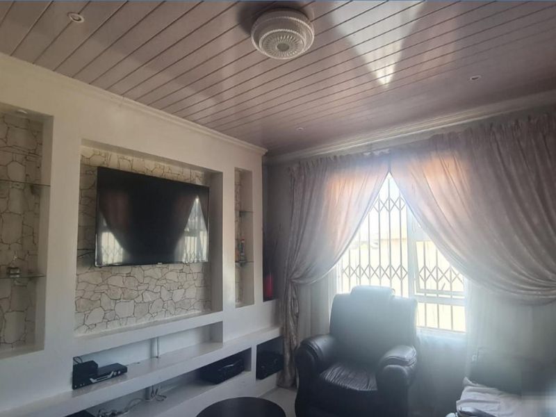 A cozy living room featuring a built-in media unit with stone-cladding accents and timber-look ceiling paneling, providing a functional entertainment space.