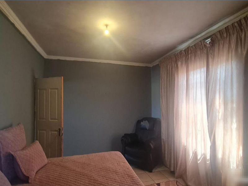 A bedroom featuring tiled flooring and crown molding, currently requiring cosmetic updates to the wall finishes.
