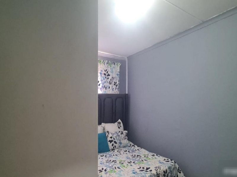A view into a bedroom featuring painted walls and a ceiling light fixture, partially obscured by a foreground wall.