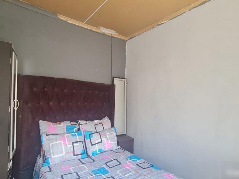 A bedroom featuring a built-in wardrobe, requiring ceiling finishing and wall repairs to improve the overall aesthetic and condition of the space.