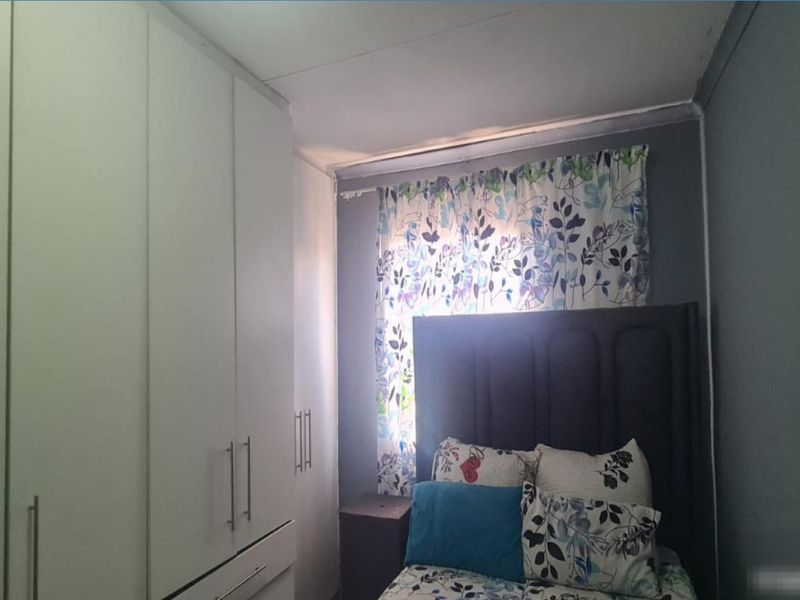 A compact bedroom featuring floor-to-ceiling built-in cupboards providing ample storage space.