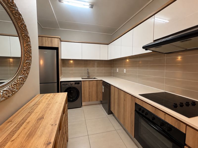 Modern kitchen featuring sleek wood-grain and white cabinetry, stone countertops, integrated appliances, and a neutral tiled backsplash.