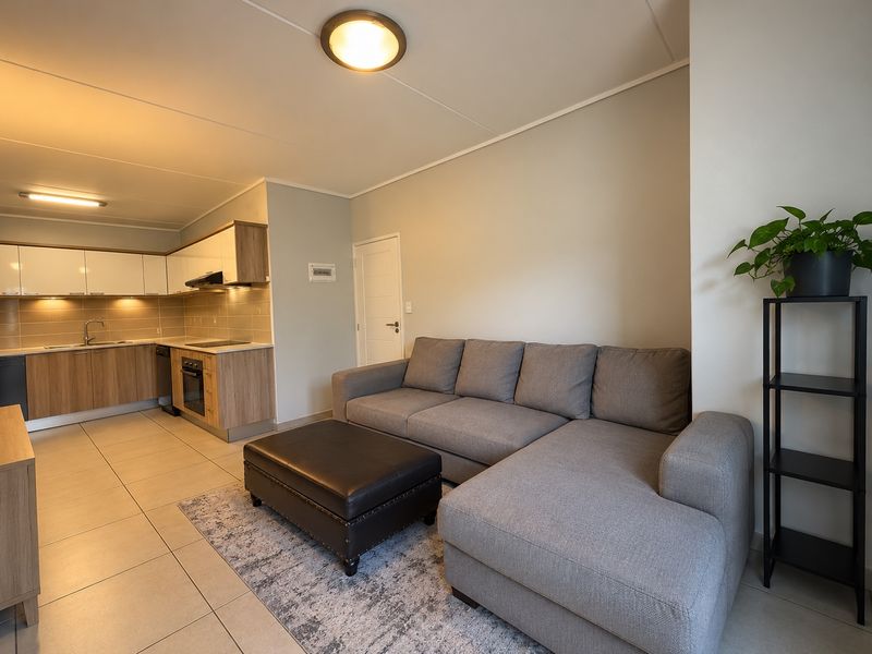 Modern open-plan living area featuring a well-appointed kitchen with integrated appliances and neutral tiled flooring throughout.