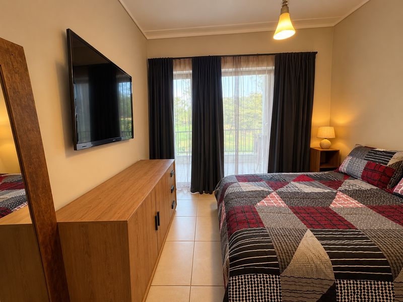 A well-maintained bedroom featuring tiled flooring, neutral wall tones, and direct access to a private balcony through sliding glass doors.