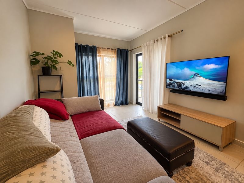A well-maintained living room featuring tiled flooring and a sliding glass door providing access to the exterior.