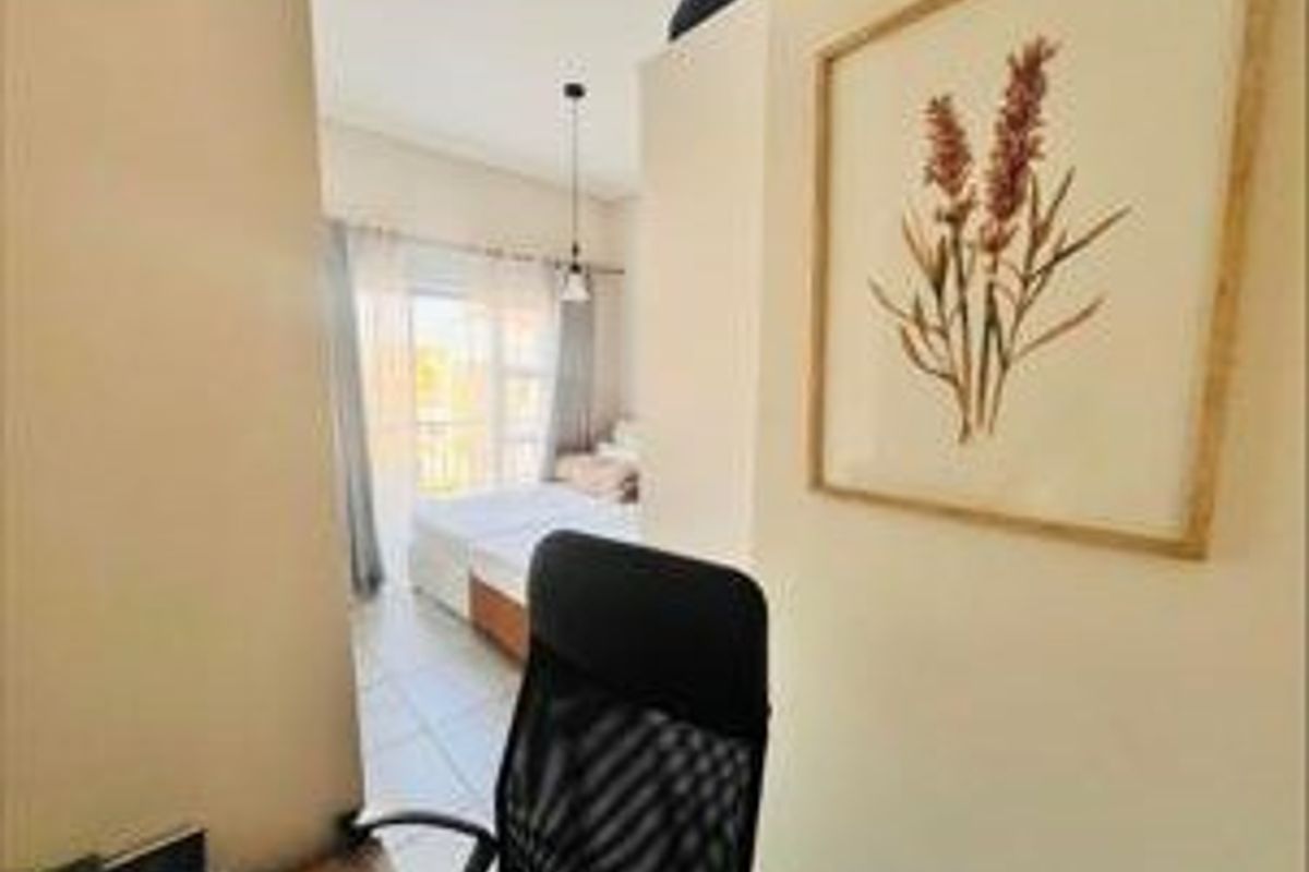 A view from a small workspace looking into a bedroom featuring tiled flooring and a sliding glass door leading to an outdoor area.