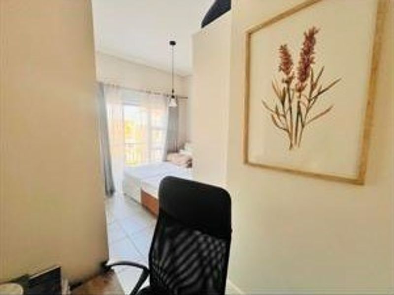 A view from a small workspace looking into a bedroom featuring tiled flooring and a sliding glass door leading to an outdoor area.