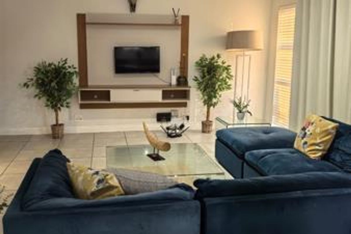A comfortable living room featuring tiled flooring, a built-in media console, and recessed ceiling lighting, creating a functional and inviting space.