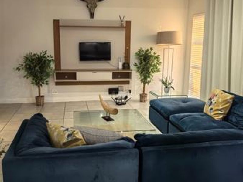 A comfortable living room featuring tiled flooring, a built-in media console, and recessed ceiling lighting, creating a functional and inviting space.