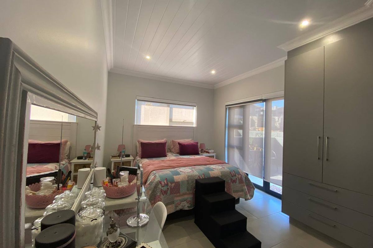 A well-maintained bedroom featuring modern built-in cupboards, tiled flooring, a tongue and groove ceiling, and direct access to an outdoor area via sliding doors.