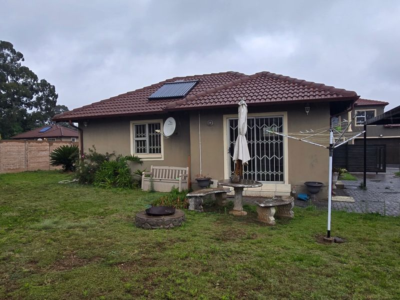 Rear view of the cluster home featuring a private garden, paved area with carport, solar water heating system, and secure access points.