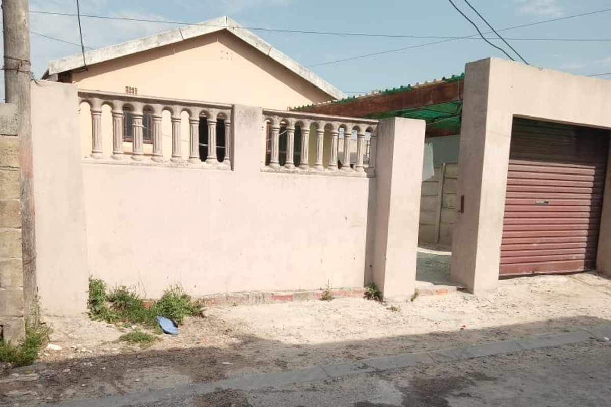 Front exterior view of the property featuring a boundary wall with balustrades and a roller shutter garage door.