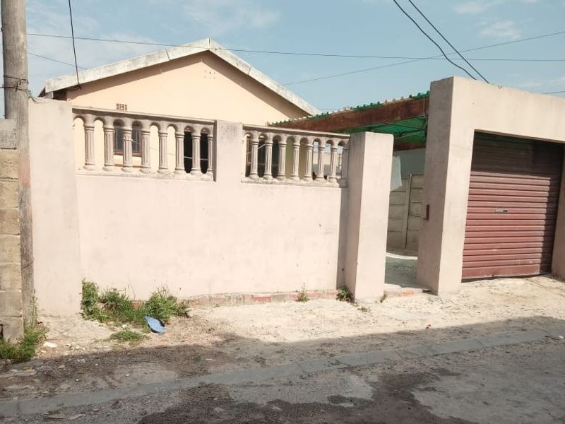Front exterior view of the property featuring a boundary wall with balustrades and a roller shutter garage door.