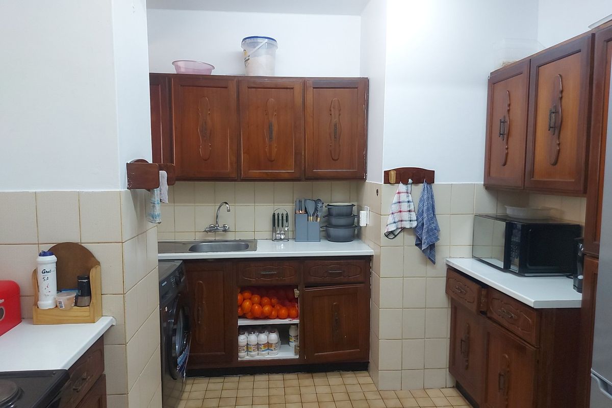 A functional kitchen featuring traditional wooden cabinetry, tiled backsplash, and tiled flooring, offering a classic layout with integrated storage and workspace.