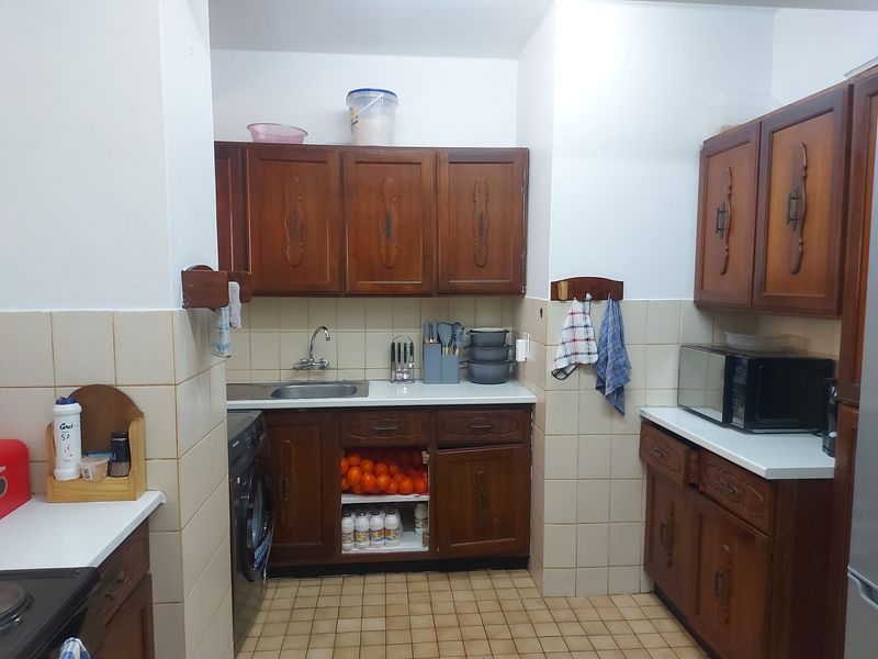 A functional kitchen featuring traditional wooden cabinetry, tiled backsplash, and tiled flooring, offering a classic layout with integrated storage and workspace.