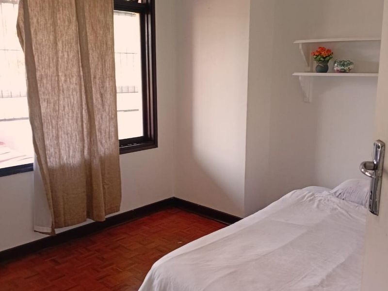 A bedroom featuring warm parquet flooring, a ceiling fan, and built-in wall shelving, offering a functional and cozy living space.