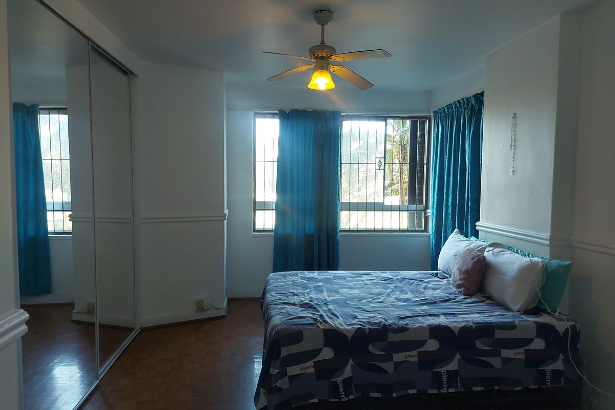 A bedroom featuring parquet flooring, a ceiling fan, and a large built-in mirrored wardrobe with security bars on the windows.