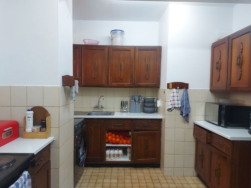 A functional kitchen featuring traditional wooden cabinetry, tiled backsplash, and tiled flooring, offering a classic layout with integrated storage and appliance space.